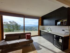 a living room with a couch and a large window at Mini casa en lo alto de la montaña in Valparaíso