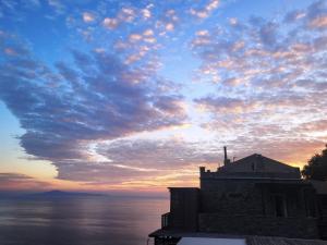 un cielo nublado sobre el agua con un edificio en Aegean Castle Andros – Adults Only, en Agia Eleousa