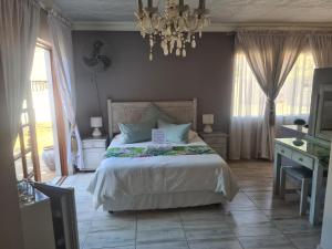 a bedroom with a large bed and a chandelier at Royal Villa Guesthouse in Brakpan