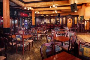 加利納的住宿－Irish Cottage Inn & Suites，一间带木桌椅的餐厅和一间酒吧