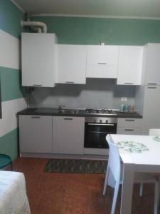 cocina con armarios blancos, mesa y fogones en Appartamento 4 - NEW, en Comezzano