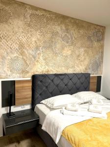 a bedroom with a large bed and a wall with at Apartman Lux-besplatno korišćenje zasebne garaže in Sremska Mitrovica