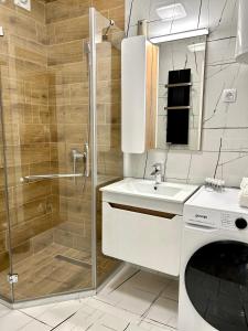 a bathroom with a shower and a sink and a washing machine at Apartman Lux-besplatno korišćenje zasebne garaže in Sremska Mitrovica