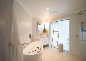 baño con bañera, lavabo y escalera en Beach House! 4 Bed Holiday Home Near Byron Bay, en Mullumbimby