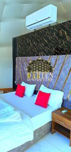 Darien Luxury Camp في وادي رم: سرير مع وسادتين حمراء في الغرفة