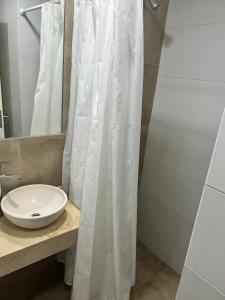 a bathroom with a white shower curtain and a sink at Art Gallery Pilar in Pilar