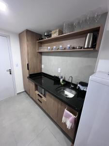 - une cuisine avec un évier et un comptoir noir dans l'établissement Studio GO Poços, à Poços de Caldas