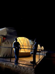 zwei Personen stehen auf einer Bühne mit einem Zelt in der Unterkunft Darien Luxury Camp in Wadi Rum