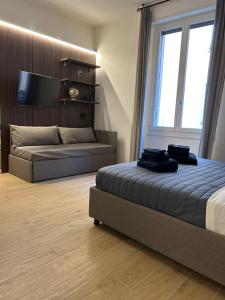 a bedroom with a bed and a couch and a tv at ALBARI HOUSE in Bologna