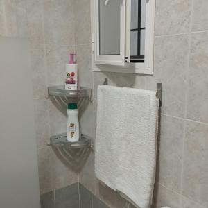 baño con toalla blanca y espejo en APARTAMENTO SOL, en Chipiona