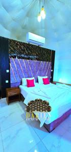 a bedroom with a large bed with pink and purple pillows at Darien Luxury Camp in Wadi Rum