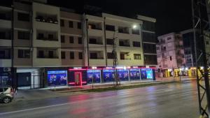a building with lit up signs on a street at night at Apartman Lux-besplatno korišćenje zasebne garaže in Sremska Mitrovica
