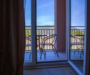 balcón con mesa y sillas y vistas a la ventana en Apart Hotel Gondola Kolasin en Kolašin