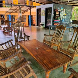 Casa Pura Vida Surf Hostel - Tamarindo Costa Rica في تاماريندو: طاولة وكراسي خشبية في الغرفة