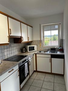 eine Küche mit weißen Schränken, einer Spüle und einer Mikrowelle in der Unterkunft Ferienwohnung in Erzingen Klettgau in Klettgau