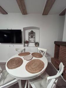 einen weißen Esstisch mit Stühlen und einen TV in der Unterkunft Studio Alexandra in Săcele
