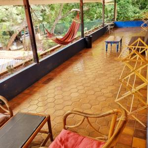 Casa Pura Vida Surf Hostel - Tamarindo Costa Rica في تاماريندو: غرفة بها أرجوحة وطاولة وكراسي