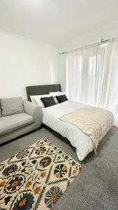 a bedroom with a bed and a couch and a rug at 2 Bed Luxury Apt in Gravesend in Kent