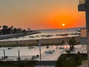 a sunset over a beach with umbrellas and the ocean at Scandic Resort One Bedroom Apartment in Hurghada
