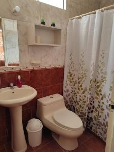 y baño con aseo, lavamanos y cortina de ducha. en Casa moderna con cochera en San Isidro Trujillo, en Trujillo