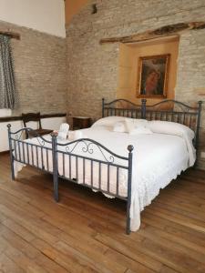Agriturismo 'Rian d'oliva في كانيلي: غرفة نوم بسرير كبير في جدار من الطوب