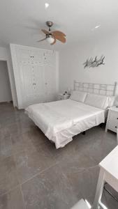 1 dormitorio con cama blanca y ventilador de techo en Precioso dormitorio en el centro de Torremolinos, en Torremolinos