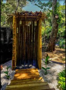a wooden gate in a garden with a tree at Cabinas de Lou Eco Lodge TAMARINDO in Santa Rosa