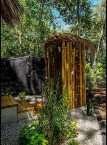 a wooden shed with a straw roof in a garden at Cabinas de Lou Eco Lodge TAMARINDO in Santa Rosa