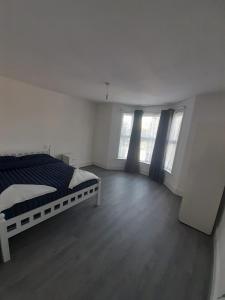 a white bedroom with a bed and two windows at RAYAN'S LODGE STRATFORD in London