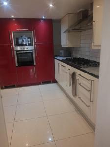 a kitchen with red cabinets and white tile floors at RAYAN'S LODGE STRATFORD in London