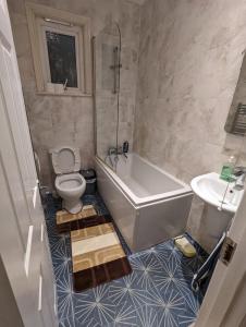 a bathroom with a tub and a toilet and a sink at RAYAN'S LODGE STRATFORD in London +30 photos