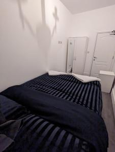 a black and white bed in a white room at RAYAN'S LODGE STRATFORD in London