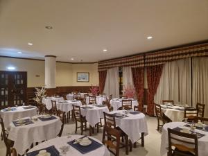 una sala da pranzo con tavoli e sedie bianchi di Hotel Peninsular a Monte Real