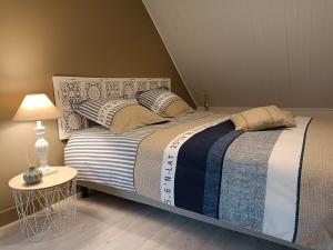 a bedroom with a large bed with a table and a lamp at L'Escale Portaise in Port-en-Bessin-Huppain