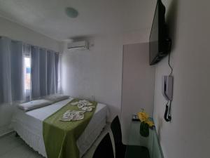a bedroom with a bed with a table and a television at Casamar Pousada in Paulista