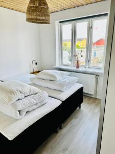Skøn villalejlighed i Skagen med terrasse og tæt på centrum في سكاغن: سريرين في غرفة بها نافذتين