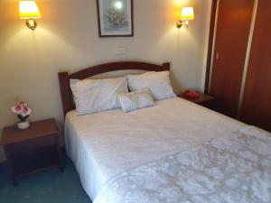 1 dormitorio con 1 cama blanca con 2 mesas y 2 lámparas en Hotel Peninsular, en Monte Real