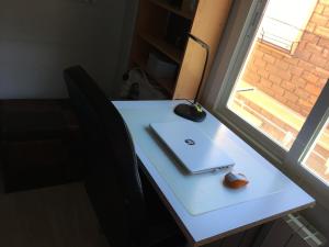 a table with a laptop and a mouse and a window at Habitación particular,baño compartido in Zaragoza