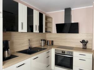 a kitchen with white cabinets and a sink at Vulkanoase Eifel - Wellness in Oberstadtfeld
