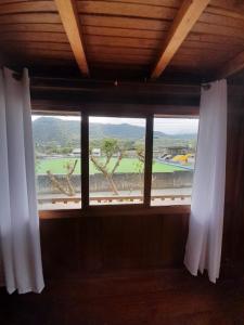 a window with white curtains and a view of a golf course at The Temple III, Mindo in Mindo