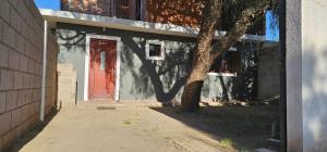 a building with a red door and a tree at Hospedaje Resiliencia in Cordoba