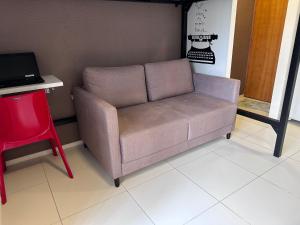 a couch in a room with a table and a red chair at Flat para 4 pessoas em Boa Viagem com Piscina, Wifi 500Mbps, localizado a 350 metros da Praia in Recife
