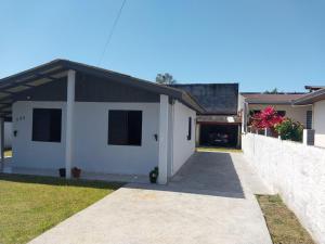 a white house with a black roof and a driveway at Casa disponível para diária, 300m do mar casa sozinha no terreno in Matinhos