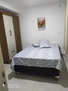 a bedroom with a bed with a blue and white comforter at Souza Lofts Centro Praça Tiradentes in Teófilo Otoni