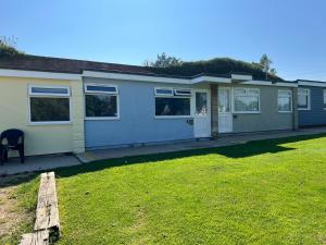 a house with a lawn in front of it at 2 Bedroom Chalet SB84, Sandown Bay, Dog Friendly in Brading