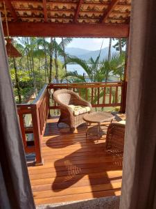 une terrasse en bois avec des chaises en osier et une table dans l'établissement Pousada Ninhal das Garças, à Ilha Comprida