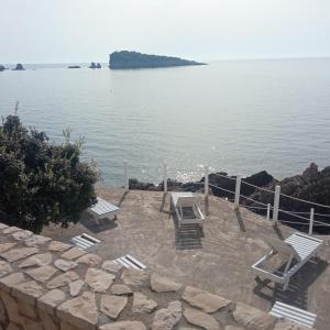 a group of chairs sitting on a patio by the water at APARTMANI LUX SEA in Utjeha