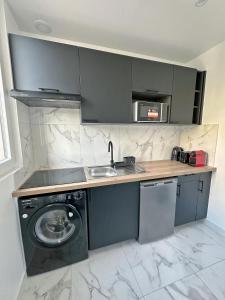 een keuken met een wastafel en een wasmachine bij Cosy Apartment near La Défense / Paris 4pers in La Garenne-Colombes