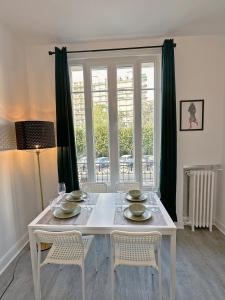 een witte eettafel met stoelen en een raam bij Cosy Apartment near La Défense / Paris 4pers in La Garenne-Colombes