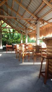 um grupo de mesas e cadeiras de madeira sob um telhado em Isla Haruhay em Dapa